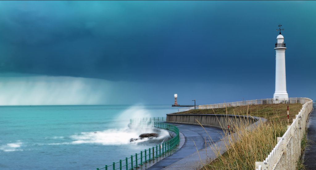 Lighthouse by turbulent sea and sky